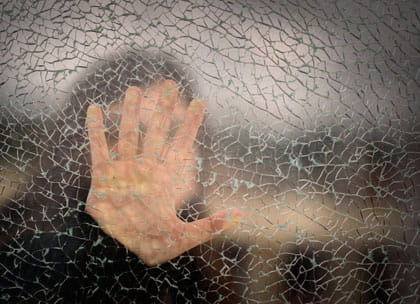 Person with hand held against shattered glass